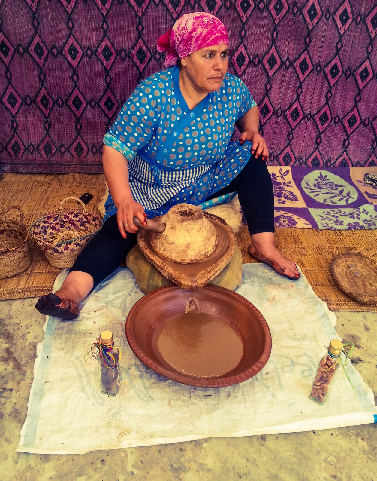 Woman using a traditional stone grinder to produce argan oil